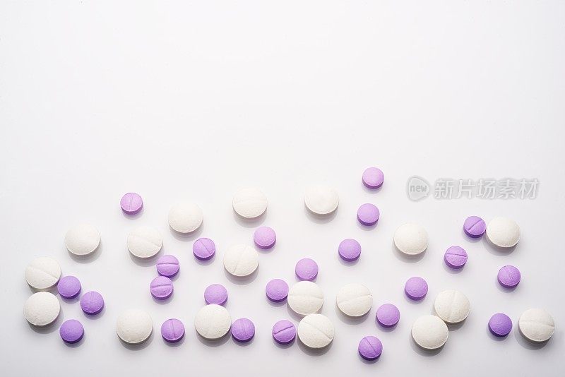 Purple and white color pills on white table.